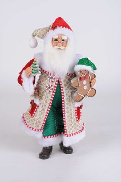 a santa clause figurine holding two gingerbreads and a christmas ornament