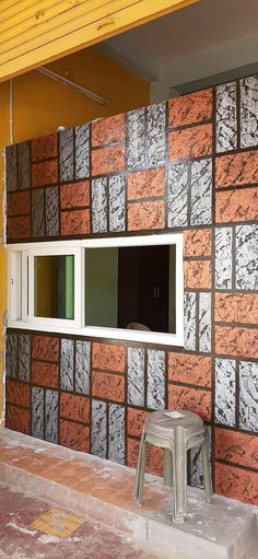 a brick wall with a window and stool in front of it, next to a building under construction