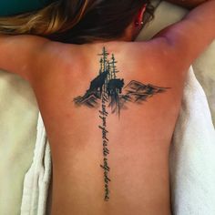 a woman laying on top of a bed with her back turned to the camera and tattoo