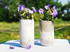 two cement vases with purple flowers in them