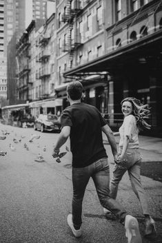 a man and woman are walking down the street with birds flying around in front of them