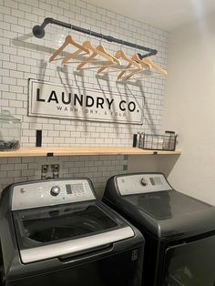 two washers and dryer in front of a laundry co sign on the wall