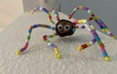 a close up of a fake spider made out of plastic beads on a white surface