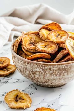 a bowl filled with sliced bananas on top of a marble counter next to slices of banana