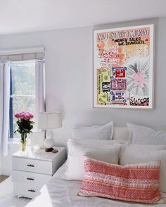 a bedroom with white bedding and pink flowers on the nightstands next to the window