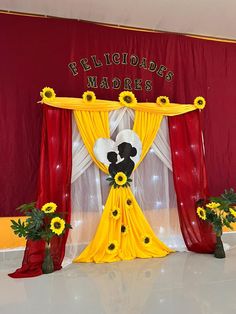 a stage set up with sunflowers and decorations for a party or event in front of a red curtain