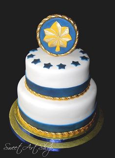 a three tiered cake with blue and gold decorations on the top, sitting on a black surface