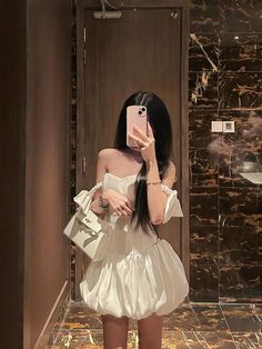 a woman taking a selfie in front of a mirror wearing a short white dress