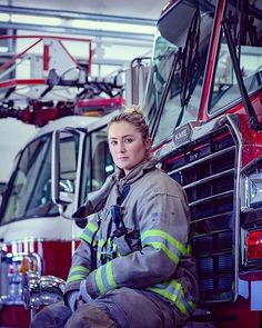 a woman sitting on the ground next to a firetruck in a garage area