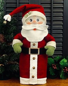 a santa clause doll standing next to a christmas tree