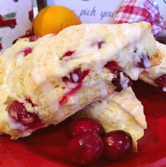 two pieces of cake on a red plate with cherries and oranges in the background