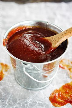 a wooden spoon in a metal bucket filled with sauce