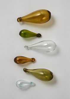 five glass bottles are lined up on a white surface, one is empty and the other has no lid