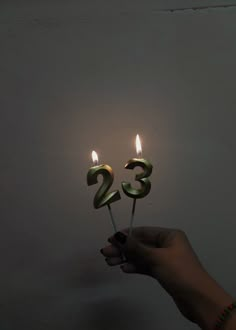 a person holding two candles with the number twenty five on them