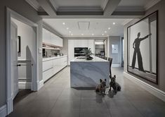 two dogs sitting in front of a kitchen island with marble counter tops and an art work on the wall