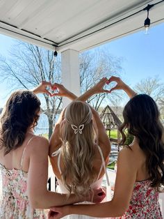 three beautiful young women standing next to each other in front of a white gazebo