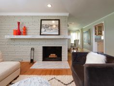 a living room filled with furniture and a fire place in front of a white brick wall