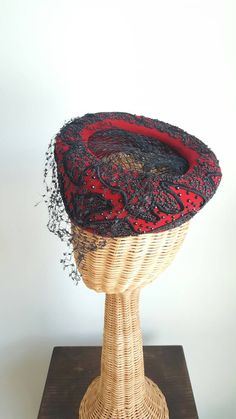 This stunning vintage hat features a striking red silk-velvet base that perches elegantly atop the head; dramatic, faceted black beading; a black net veil and center; and winding ribbon-like corde detailing. Era: 1940s Label: Macy's New York Rise: about 2.75 inches tall 7.5 inches long over top, front to back Victorian Evening Hats For Kentucky Derby, Victorian Fitted Hats For Evening, Fitted Victorian Hat For Evening, Vintage Headpieces With Curved Brim For Evening, Victorian Cloche Hat For Evening, Vintage Fitted Formal Headpieces, Vintage Evening Headpieces With Curved Brim, Vintage Cloche Headpieces For Evening, Vintage Red Party Hat