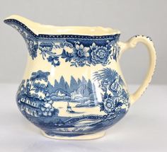 a blue and white pitcher with flowers on it