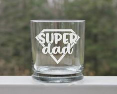 a shot glass with the words super dad printed on it sitting on a window sill