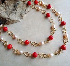 This popular style necklace is very versatile and can be worn in three ways: simply as a long single-strand necklace, doubled to appear as a double-strand necklace, or hooked mid-way to appear like a lariat necklace (see images). This is a great piece to layer with other pieces. This necklace combines beautiful red coral gemstone, with metal rings plated in 24 karat gold. The strand is high-lighted with champagne freshwater pearls. Great for the office or every-day wear. This piece is finished w Gold Necklace With Polished Red Coral Beads, Gold Single Strand Red Coral Jewelry, Elegant Red Coral Gemstone Necklace, Multi-strand Red Coral Beaded Necklace As Gift, Elegant Multi-strand Red Coral Beaded Necklaces, Ring Plate, Coral Gemstone, Maid Outfit, Double Strand Necklace