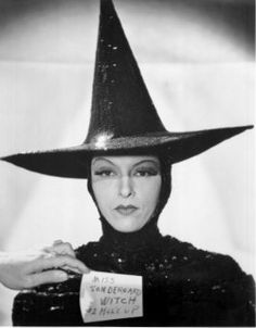 a woman wearing a witches hat holding a sign