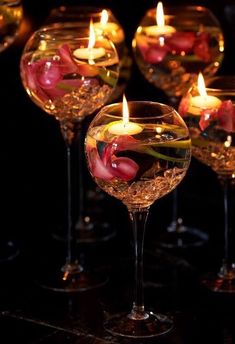 several wine glasses with candles in them on a table