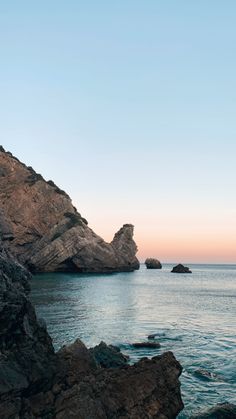 the ocean with rocks and water at sunset