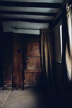 an old wooden door with curtains hanging from it's sides in a dark room