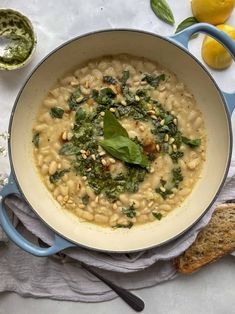 a pot filled with white beans, spinach and pesto on top of a table