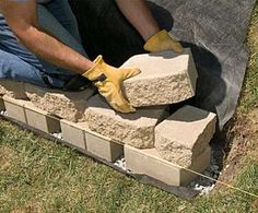 a man laying bricks on the ground with gloves and yellow rubber gloves around his feet