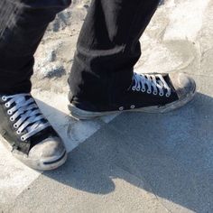 a person wearing black and white shoes standing on concrete