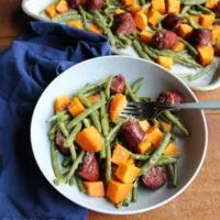 two white bowls filled with green beans and potatoes