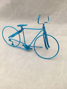 a miniature blue bicycle is shown on a white surface