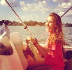 a girl is smiling while riding on a boat