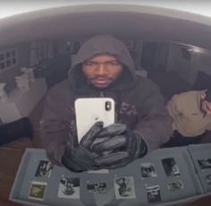 a man in a hoodie is looking at his cell phone while sitting on a table