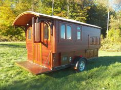 a small wooden trailer parked on top of a lush green field