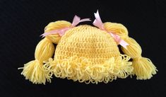 a crocheted yellow hat with pink bows on it's brimmings