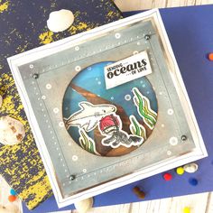 a card with an image of a fish and seaweed on it, surrounded by seashells