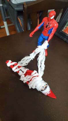 a plastic spider man is on the table next to a toy rocket that looks like it has been made out of shredded paper