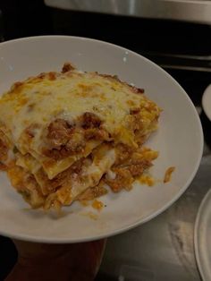 a white plate topped with lasagna covered in sauce and cheese on top of it