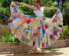 a woman in a white top is holding up a colorful piece of cloth that has been made into a skirt