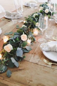 the table is set with candles and greenery for an elegant dinner or party setting