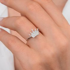 a woman's hand wearing a ring with a crown on the middle and diamonds in the middle