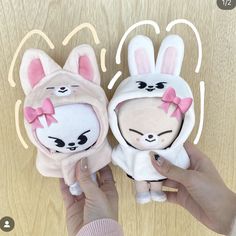 someone is holding two small stuffed animals in their hands, one has a pink bow on it's head