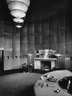 an old photo of a large room with fireplace and desks in the center, surrounded by wall - to - wall paneling