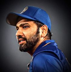 a man with a beard wearing a blue baseball uniform and a hat on his head