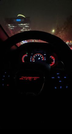 the dashboard of a car at night with city lights in the background