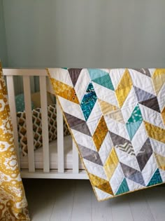 a baby crib with a quilt hanging from it's side