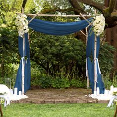 an outdoor wedding ceremony with blue draping and white flowers on the arbors